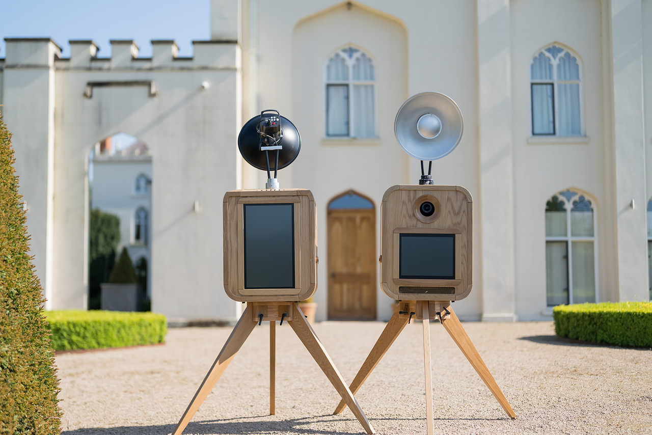 Two retro oak photo booths set up outside a wedding venue