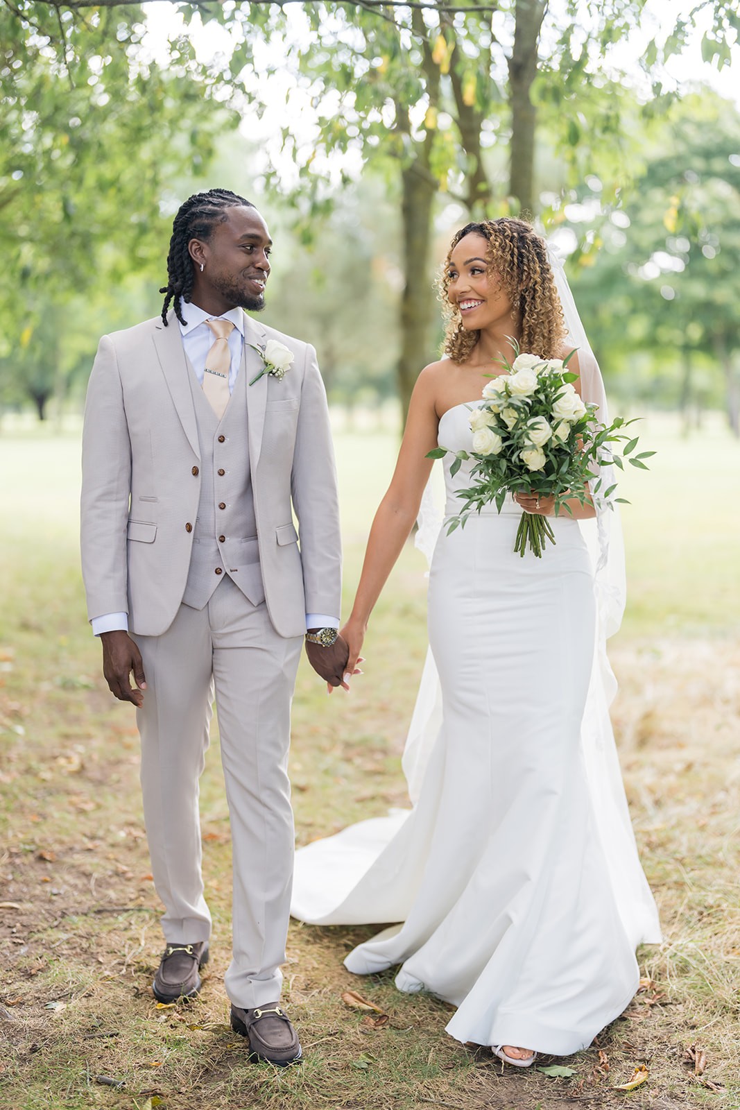 Newlyweds holding hands beneath trees