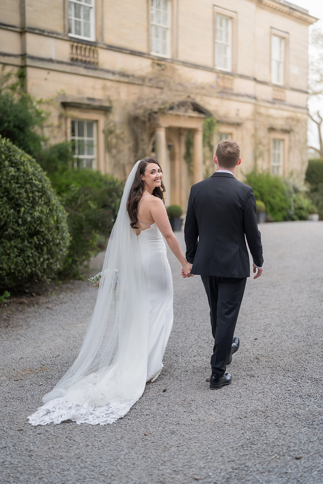 Newlyweds walking outside a stone country house