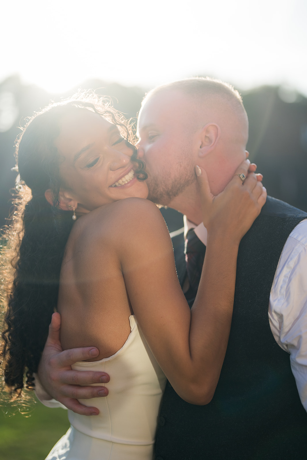 Newlyweds kissing in evening sunlight