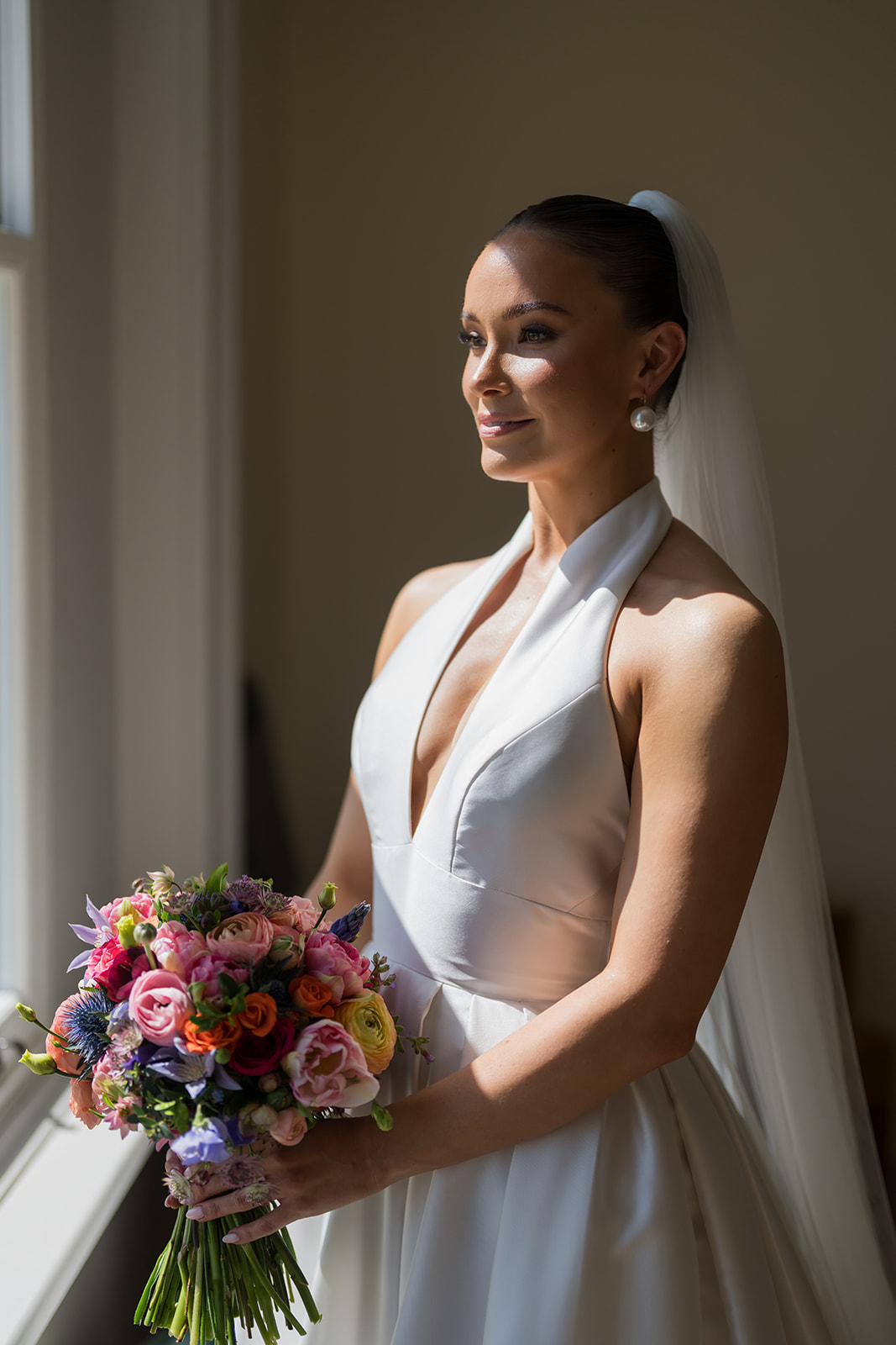 Bride holding a bouquet in dramatic window light