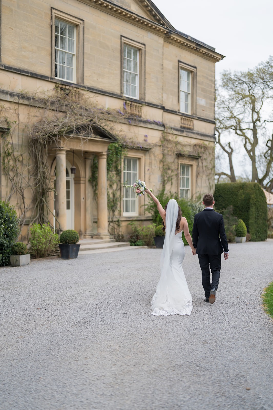 Newlyweds walking towards a stone country house