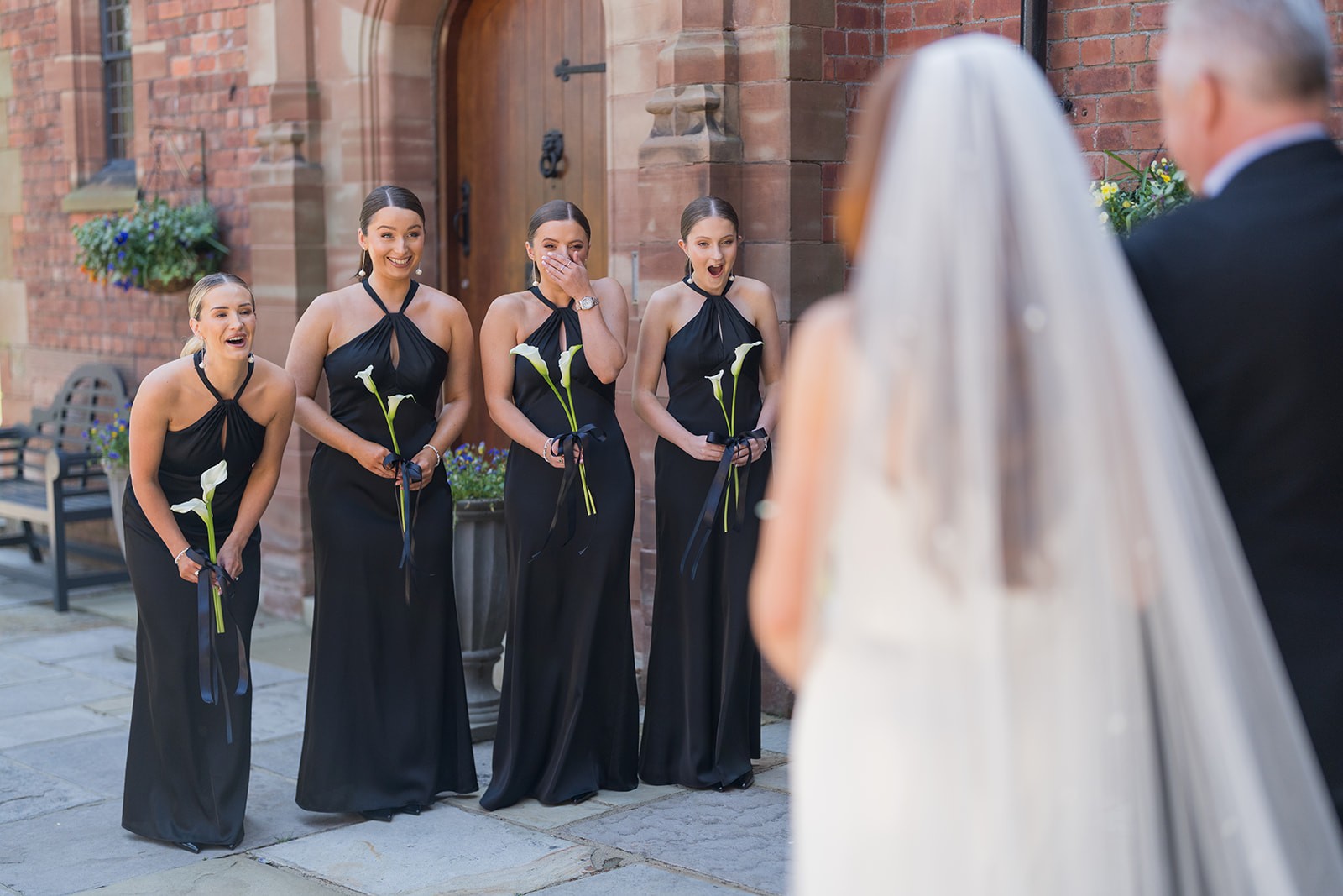 Bridesmaids reacting as they see the bride in her dress