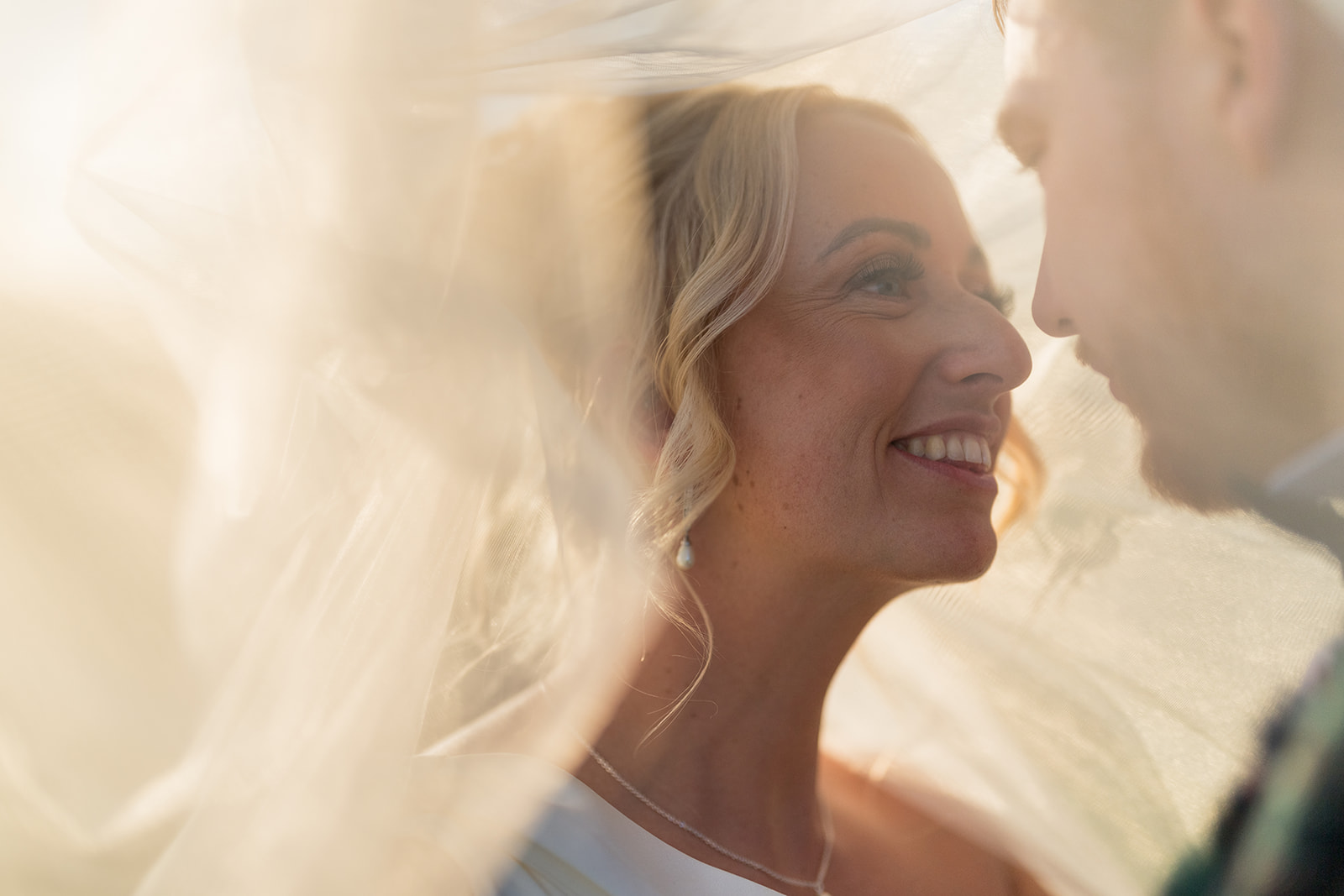 Bride smiling beneath a sunlit veil