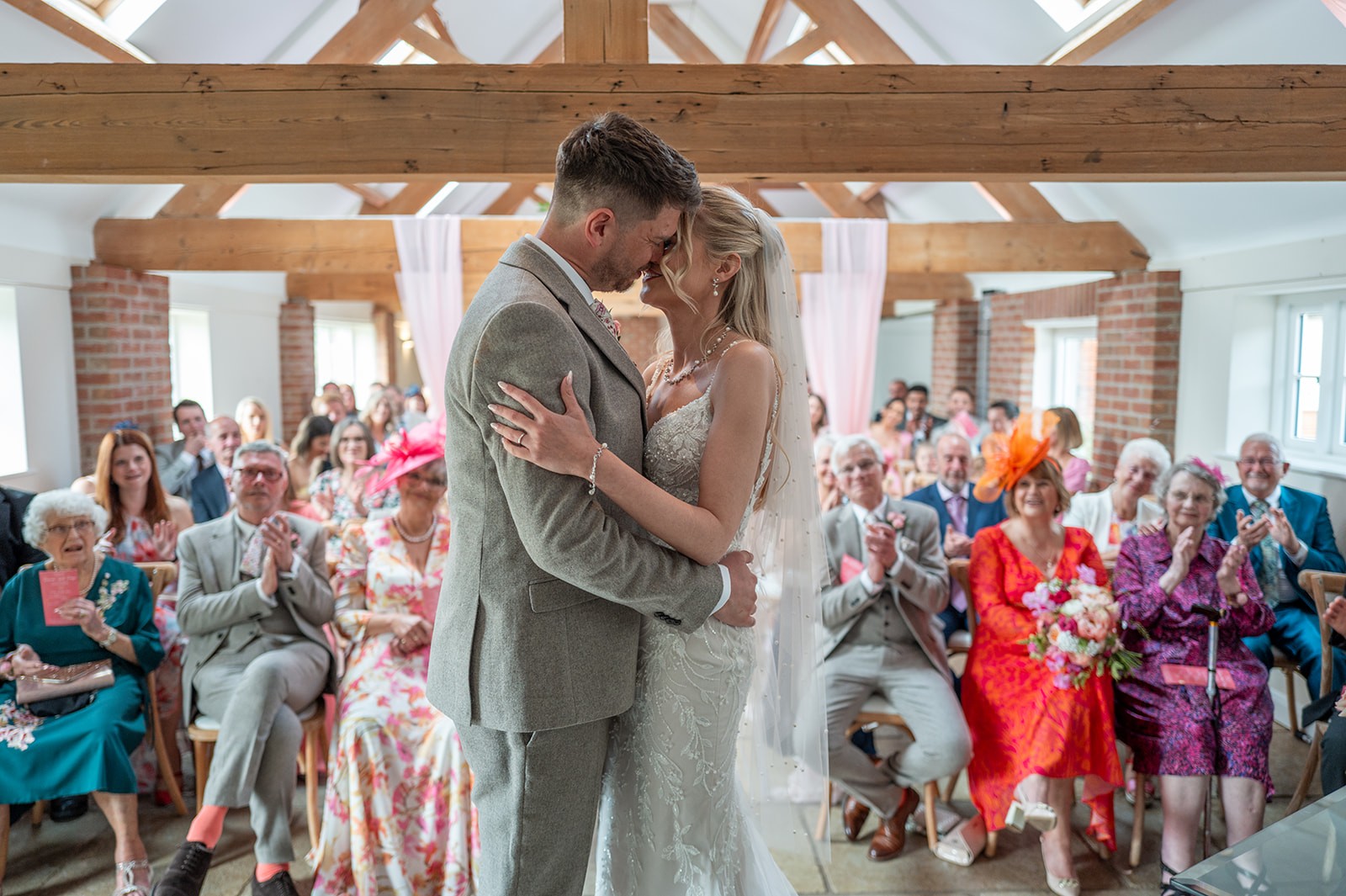 Newlyweds kissing in front of guests at a barn ceremony
