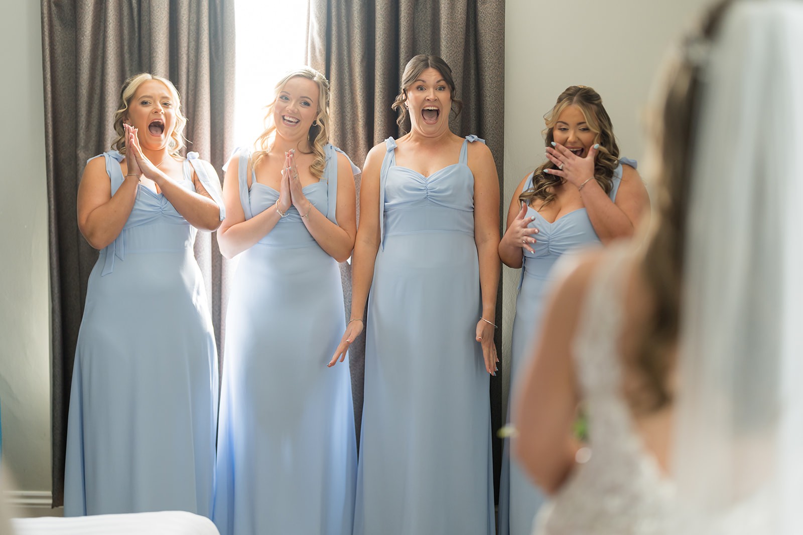 Bridesmaids reacting with delight as they see the bride