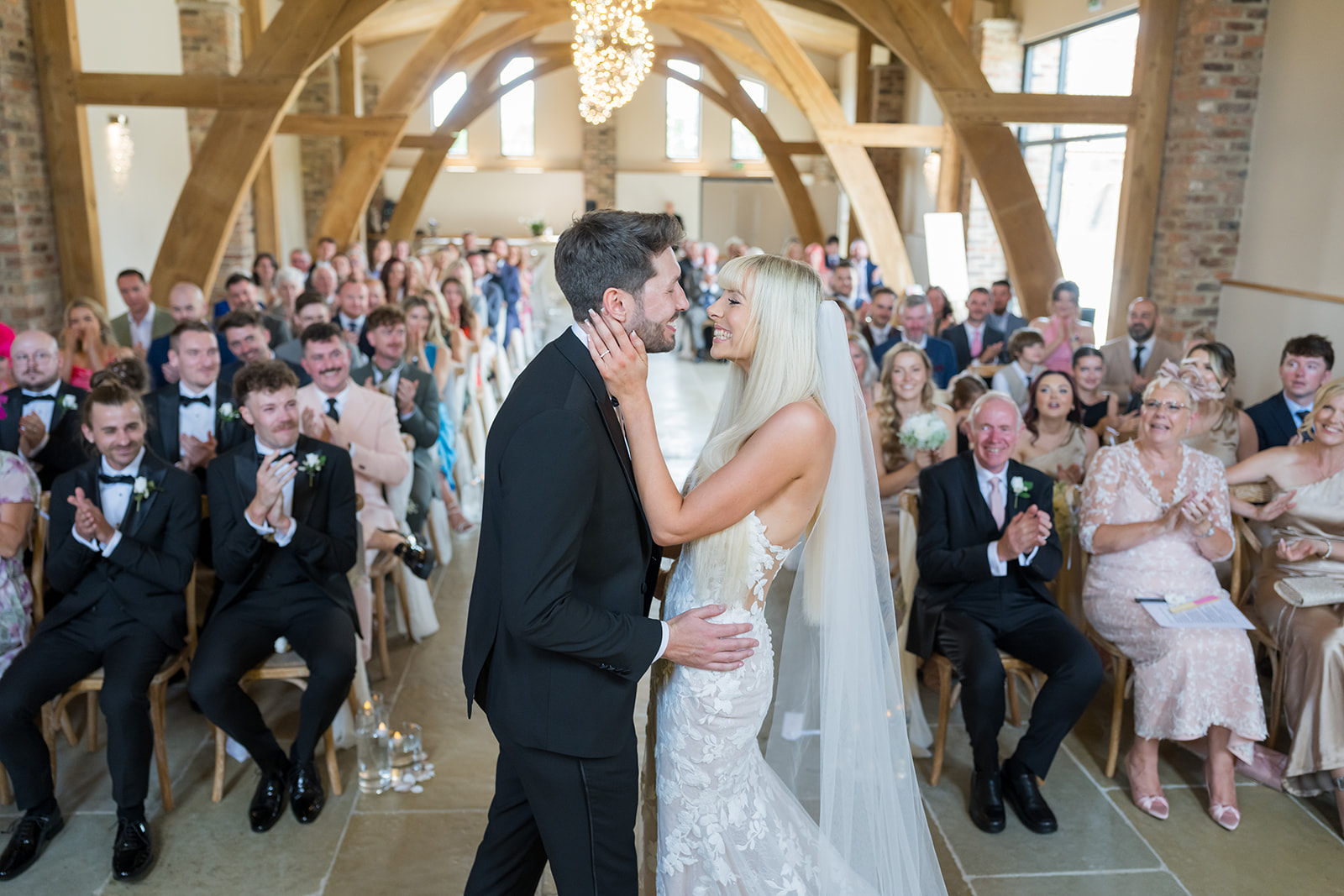Newlyweds kissing during a timber-framed barn ceremony