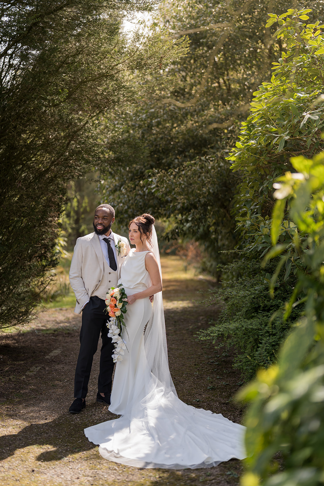 Newlyweds sharing a quiet portrait on a tree-lined path